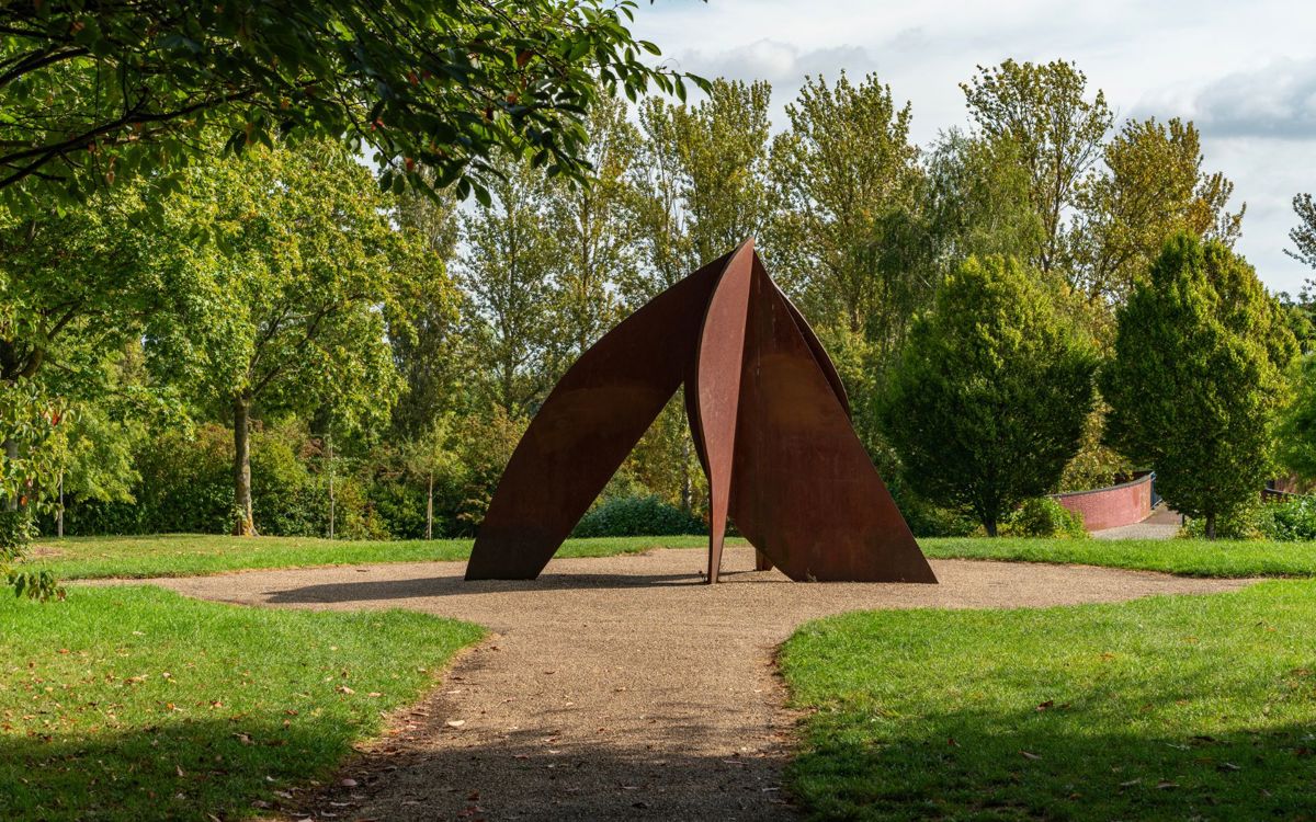 Head sculpture in Campbell Park with canal bridge in background