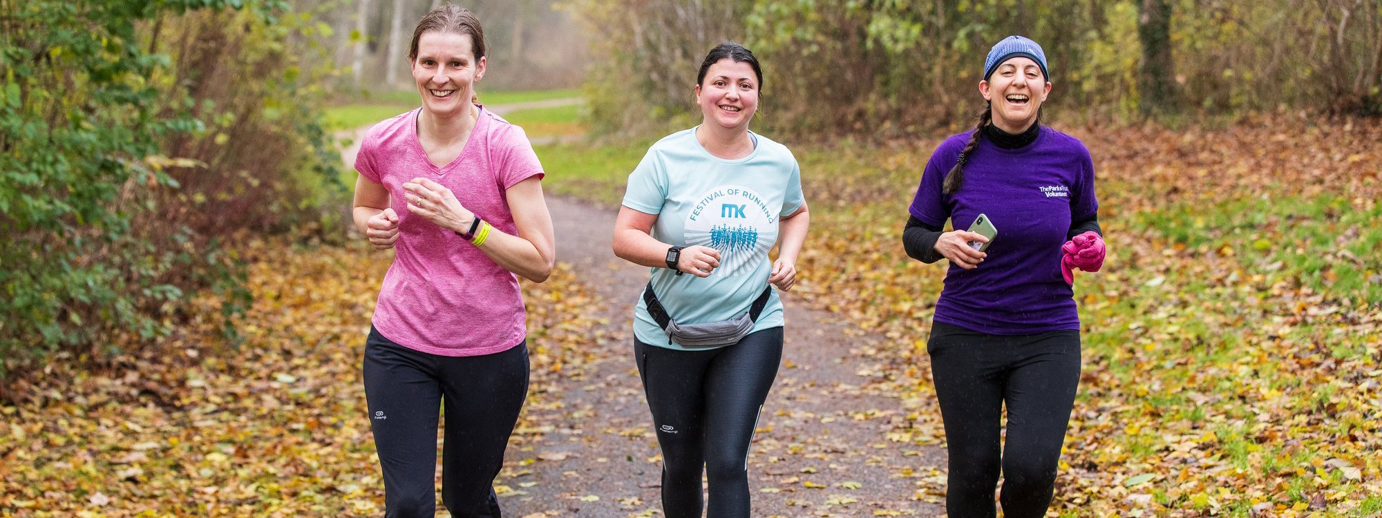 Three happy female runners in a wintery woodland setting