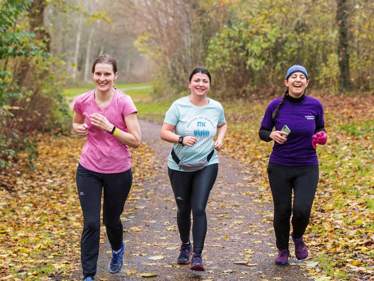 Three happy female runners in a wintery woodland setting
