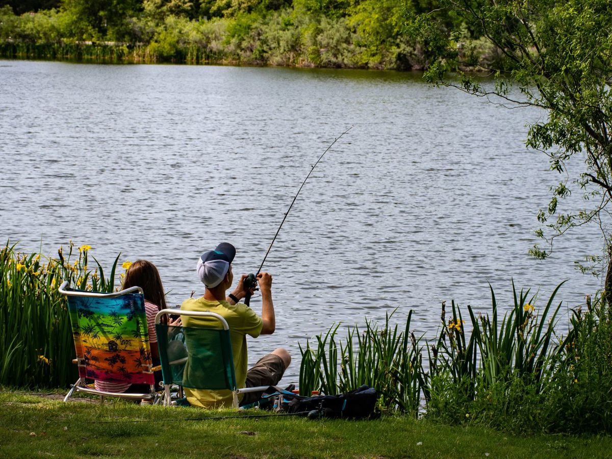 A couple fishing at a lakeside.