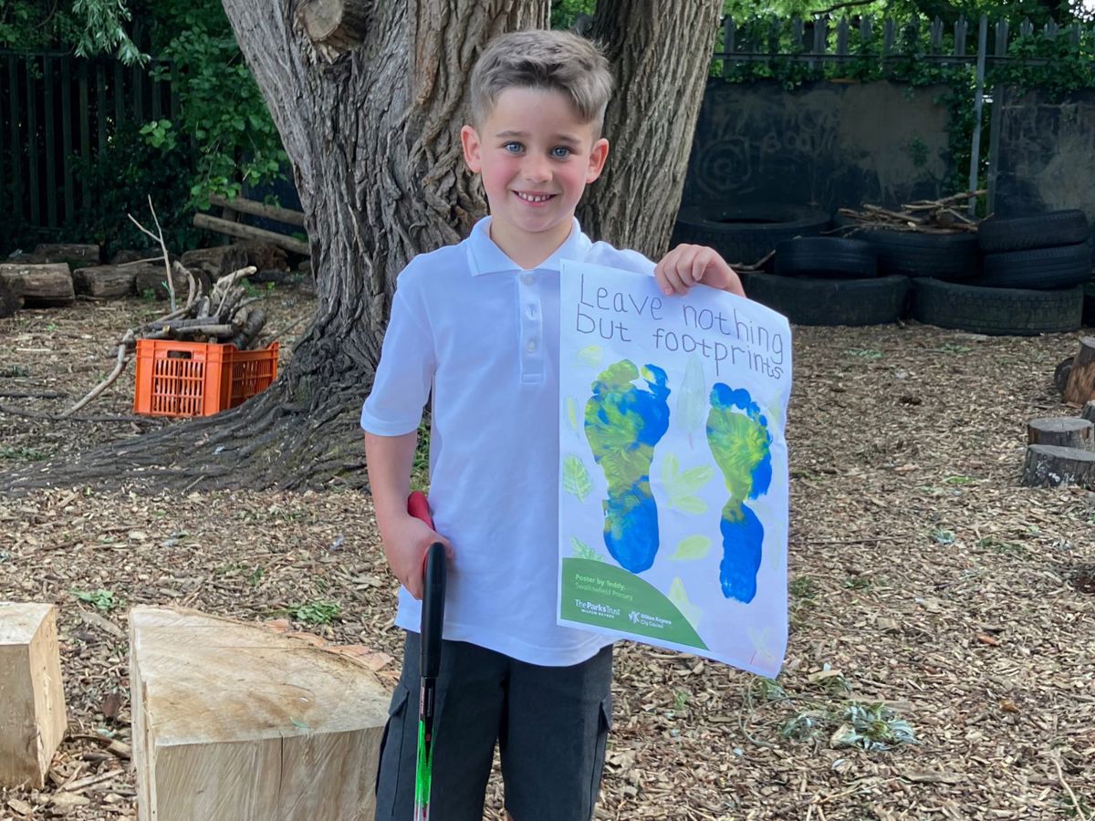 Child holding litter poster with "Leave nothing but footprints" on it
