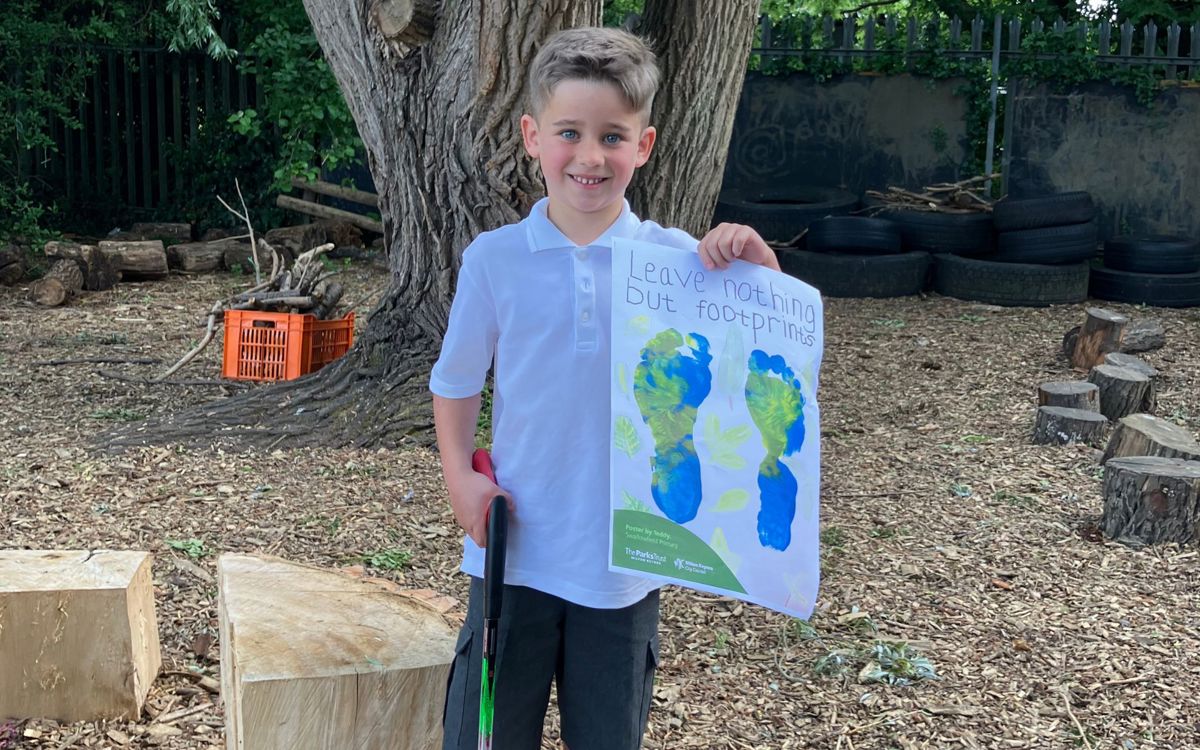 Child holding litter poster with "Leave nothing but footprints" on it