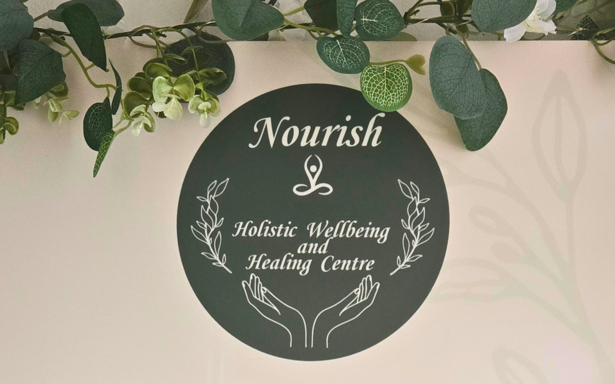 A round sign with the Nourish logo and graphics of calming hands.