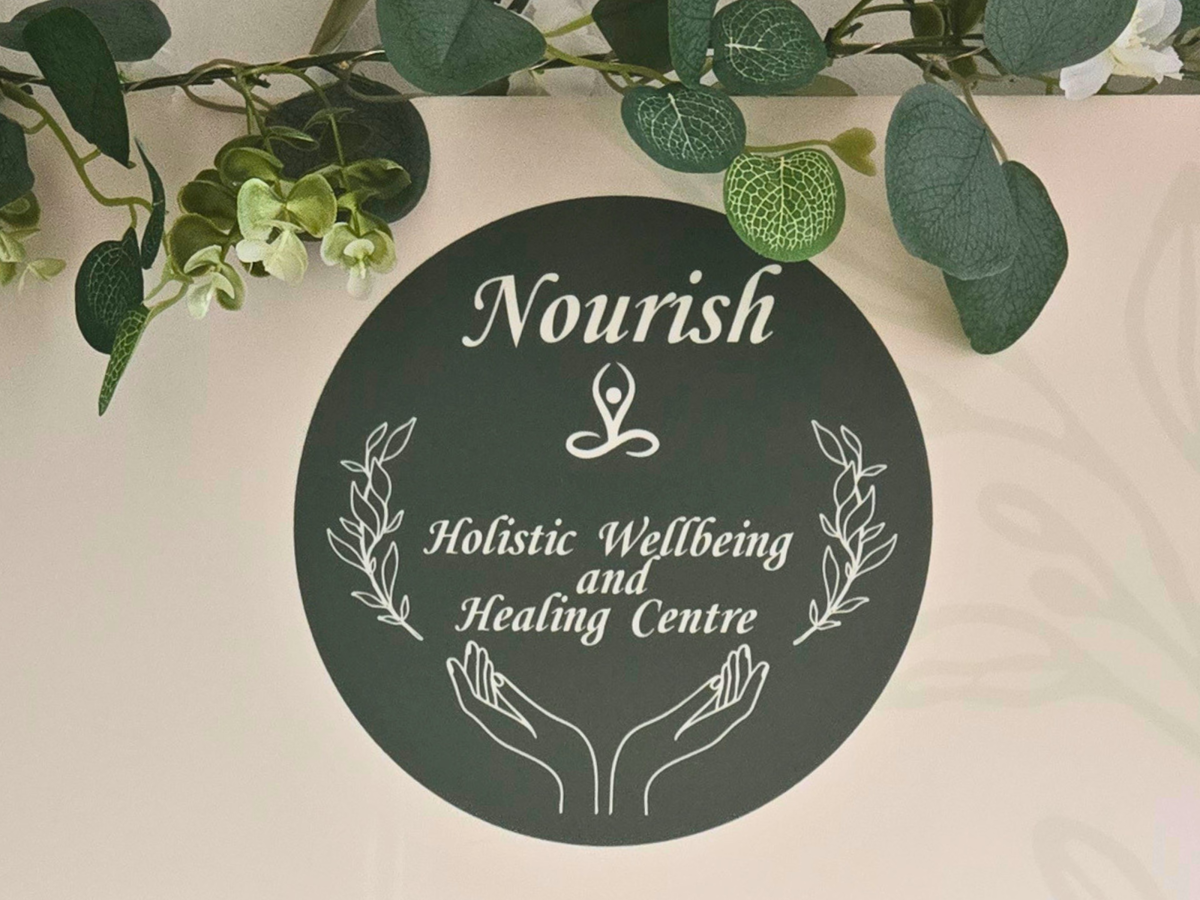 A round sign with the Nourish logo and graphics of calming hands.