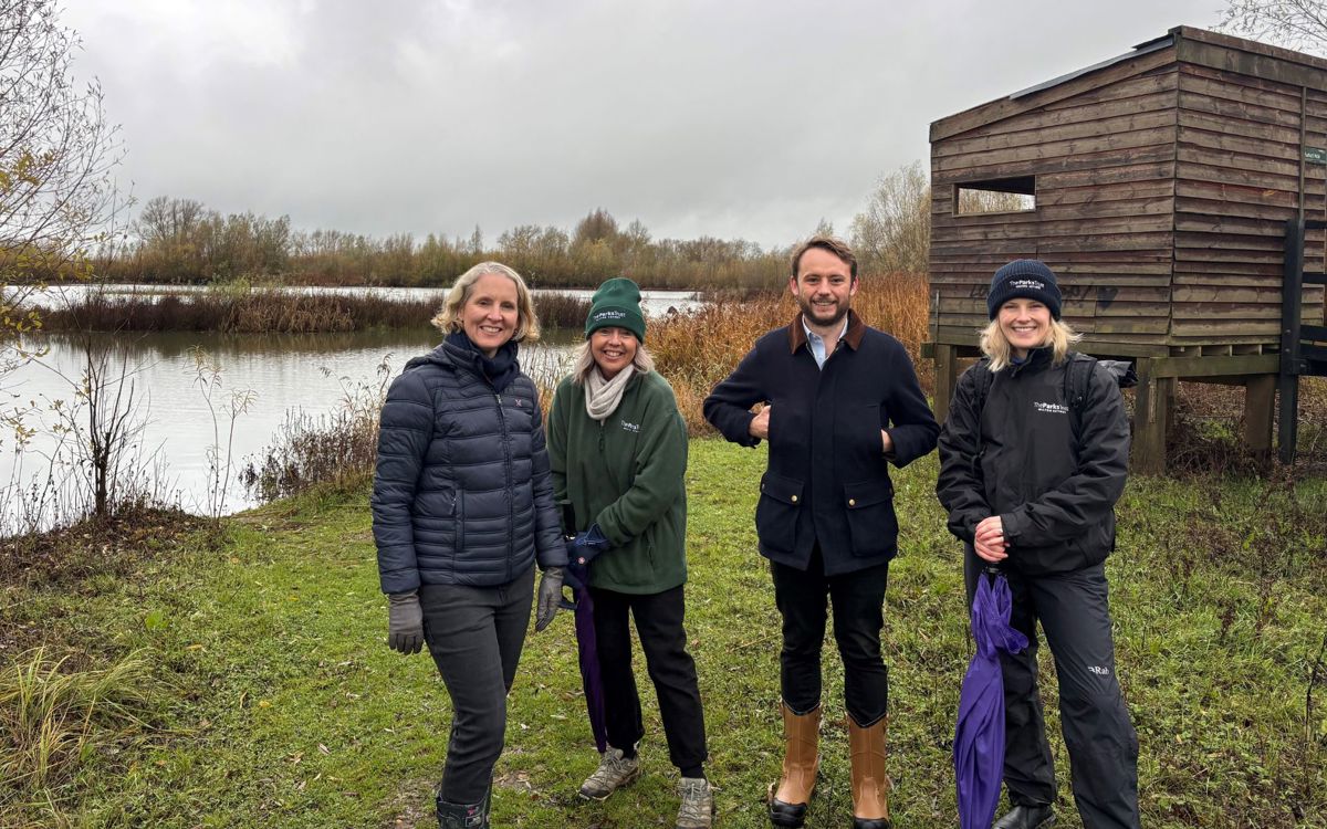 People stood in nature reserve with bird hide behind