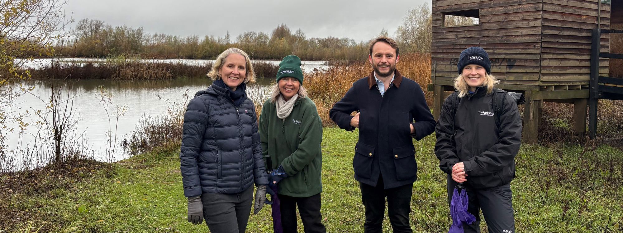 People stood in nature reserve with bird hide behind