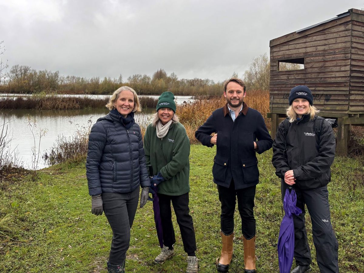 People stood in nature reserve with bird hide behind