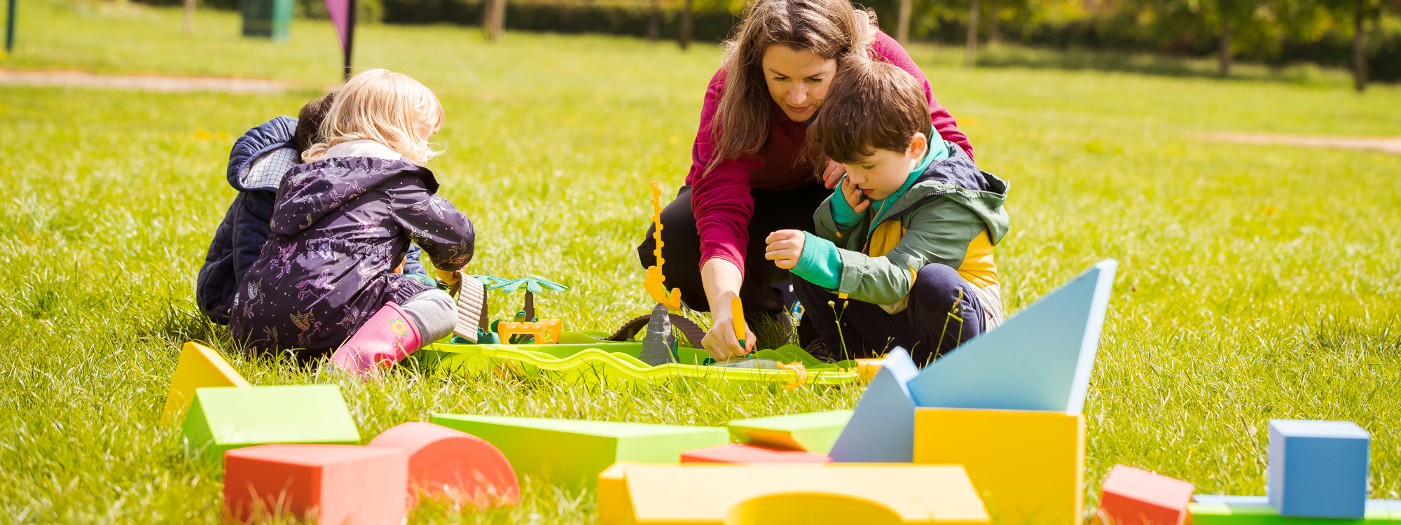 Family with three children playing on the grass on a sunny day 