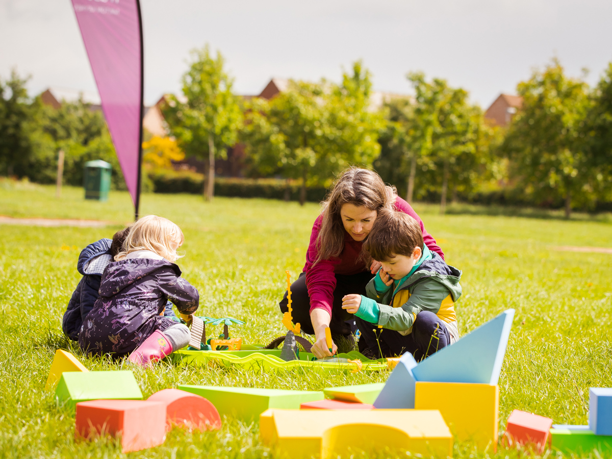 Family with three children playing on the grass on a sunny day 