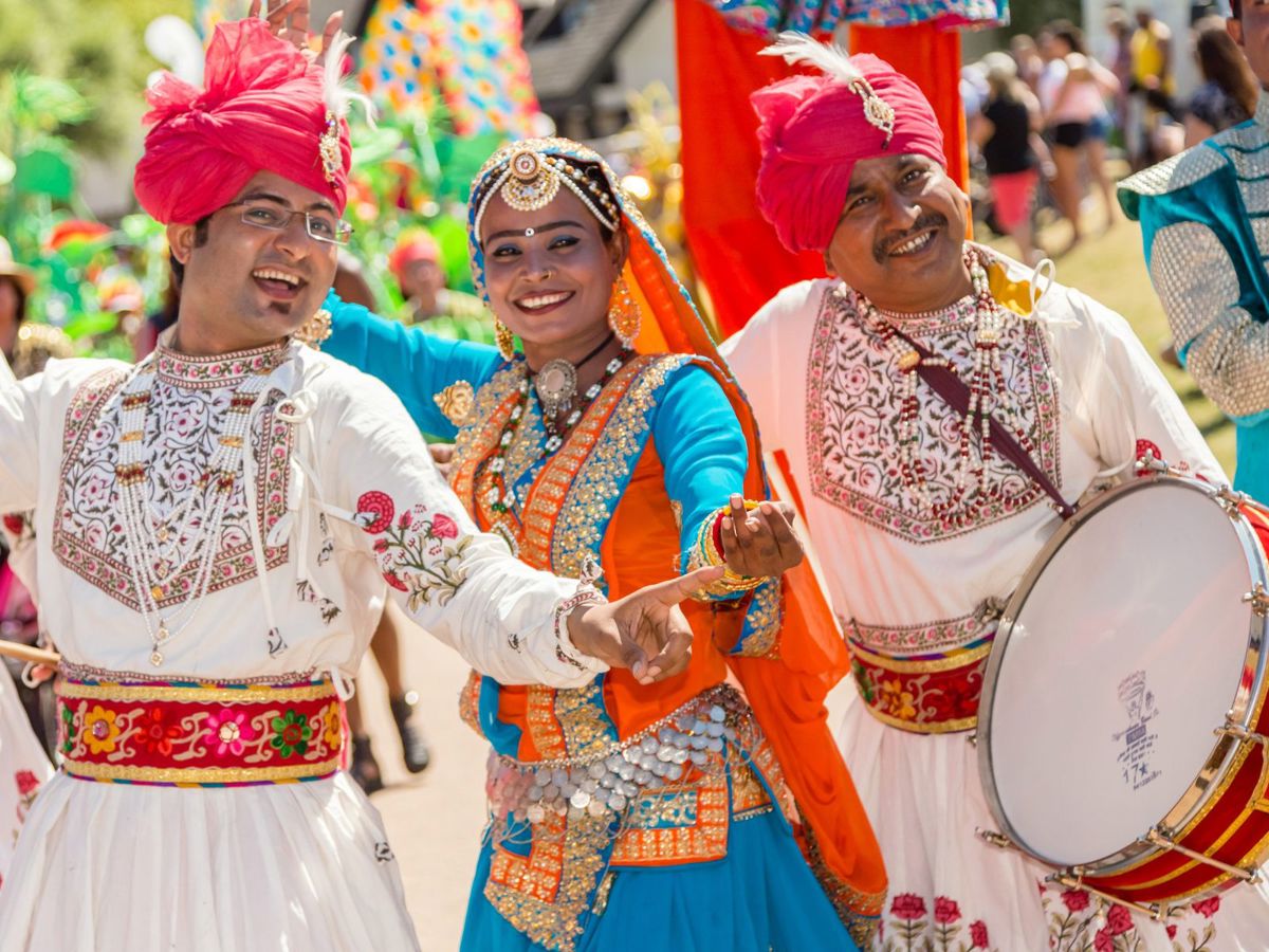 Three performers in colourful outfits smiling at the camera