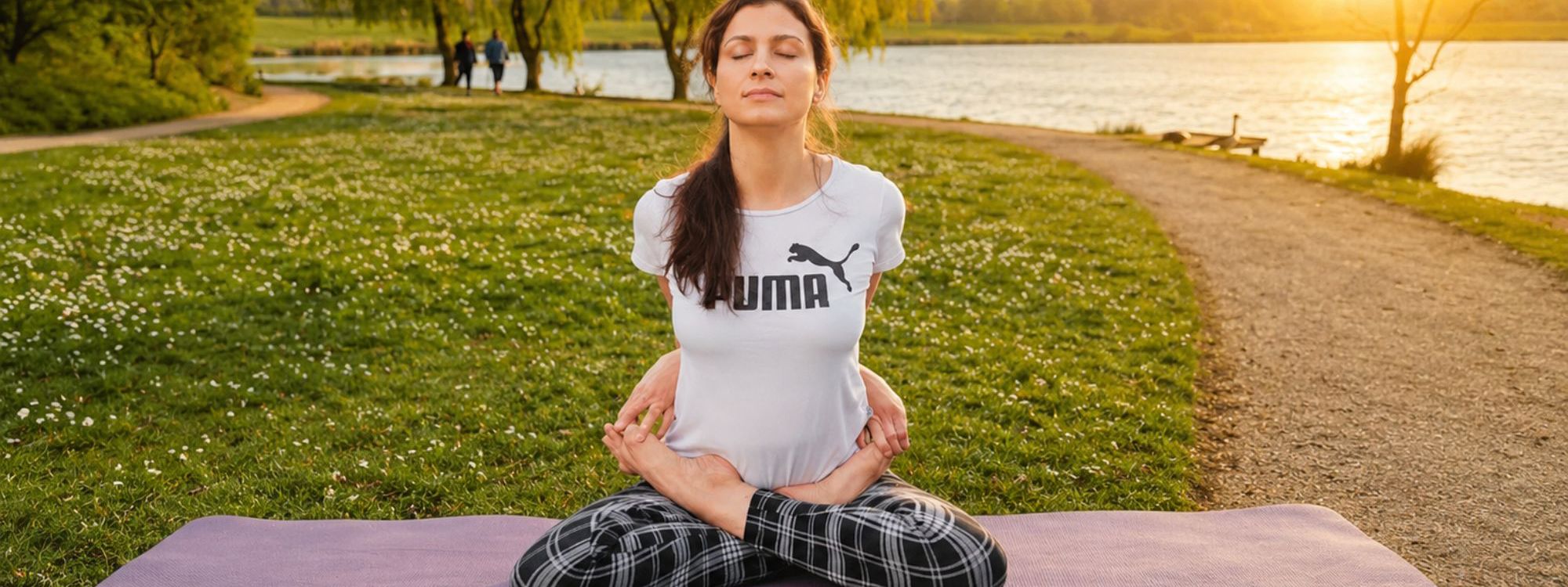 Woman on a mat doing yoga. the background displays a beautiful lake scenery with trees in the sunset