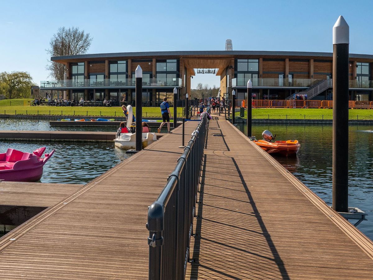 People walking on the jetty next to pedalos outside the front of the watersports centre