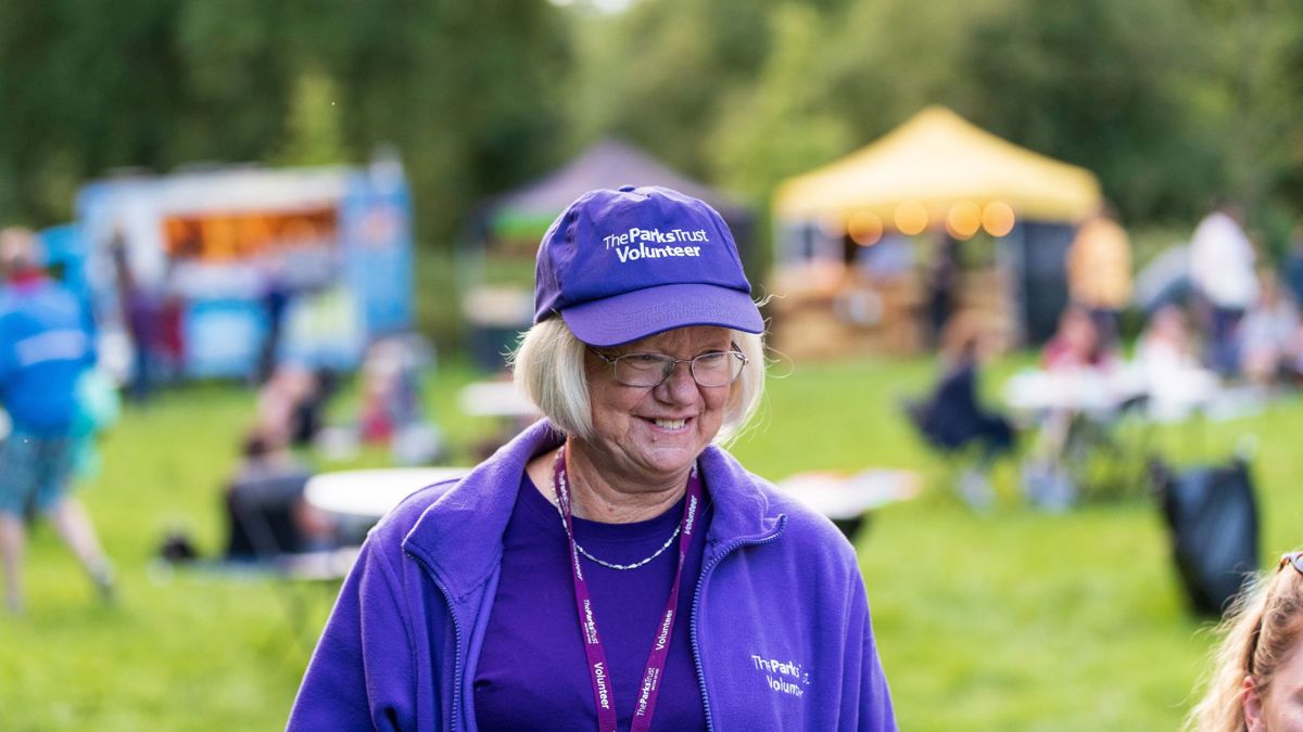The Parks Trust volunteer smiling in purple uniform