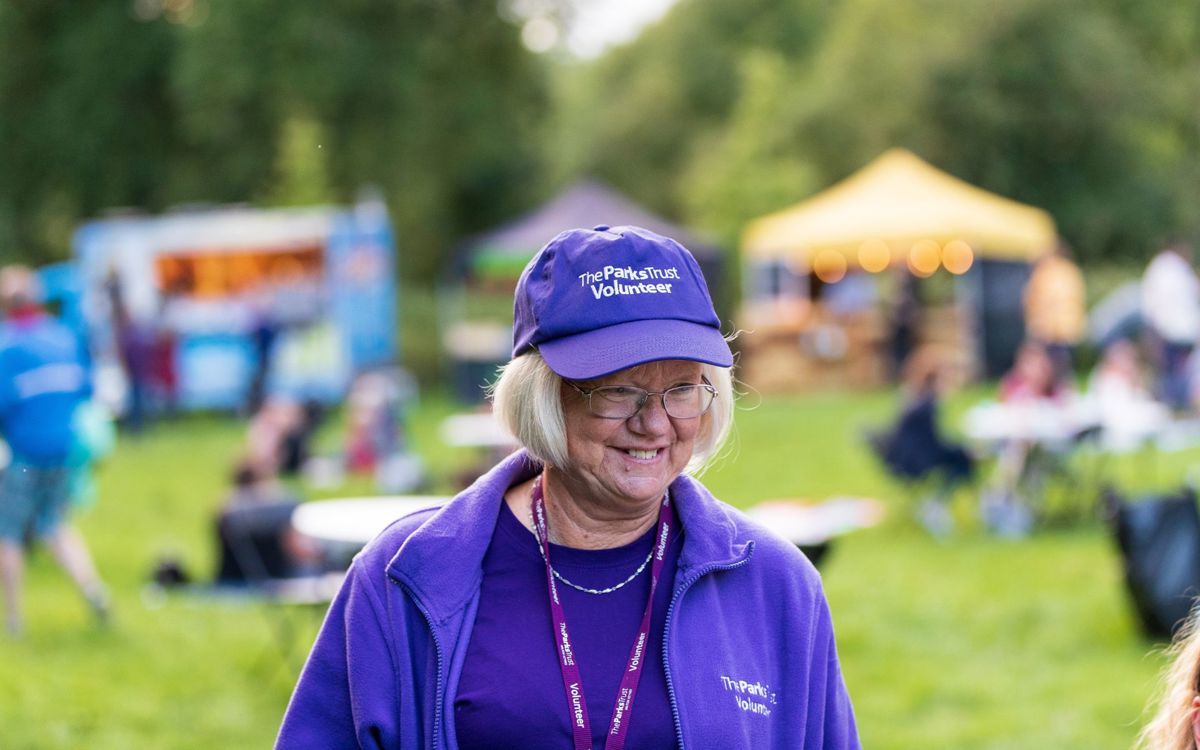 The Parks Trust volunteer smiling in purple uniform