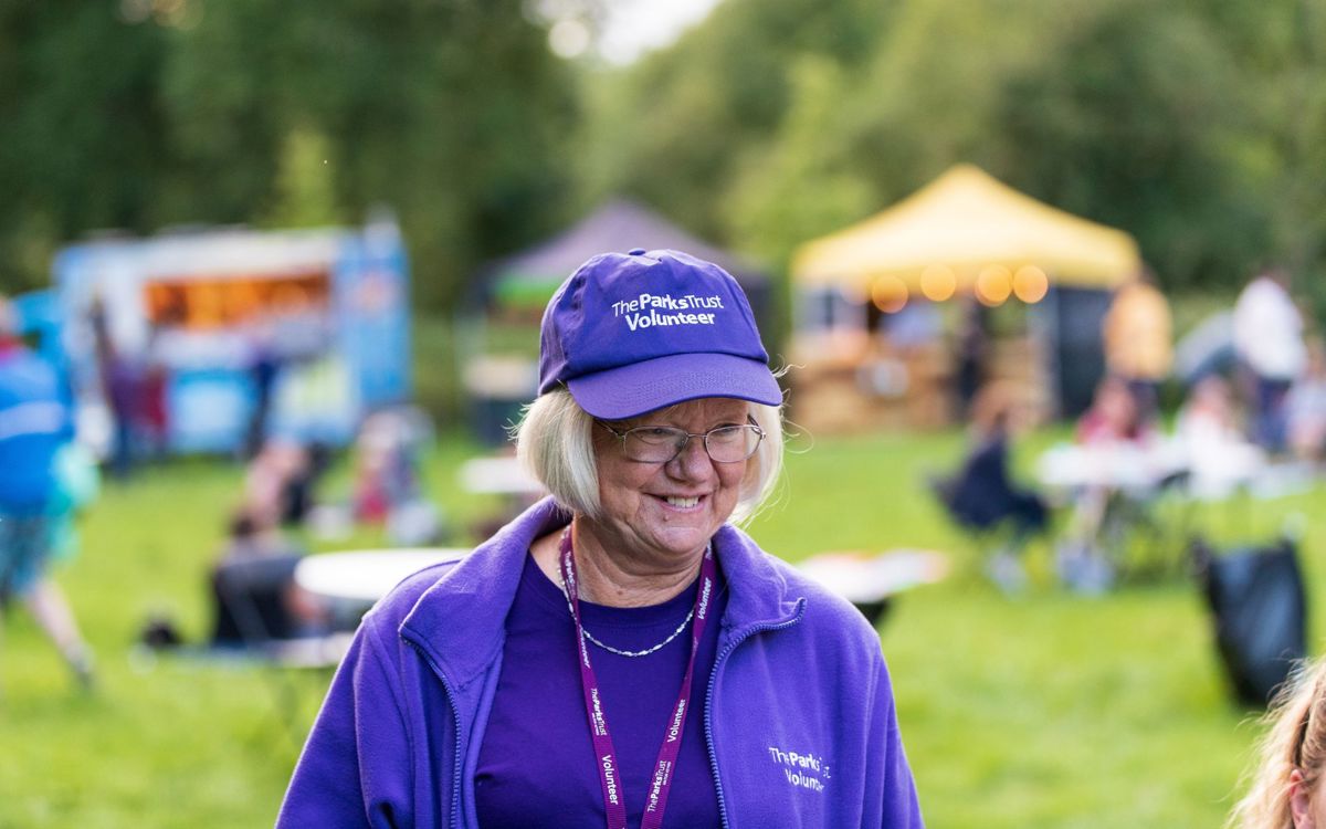 The Parks Trust volunteer smiling in purple uniform