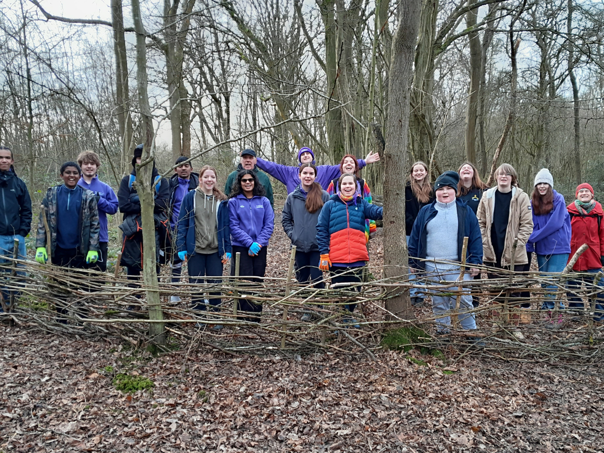 A group of teenagers stood in the woodland smiling at the camera