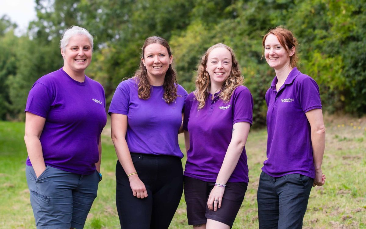 Outdoor learning team in purple Parks Trust uniform stood in park