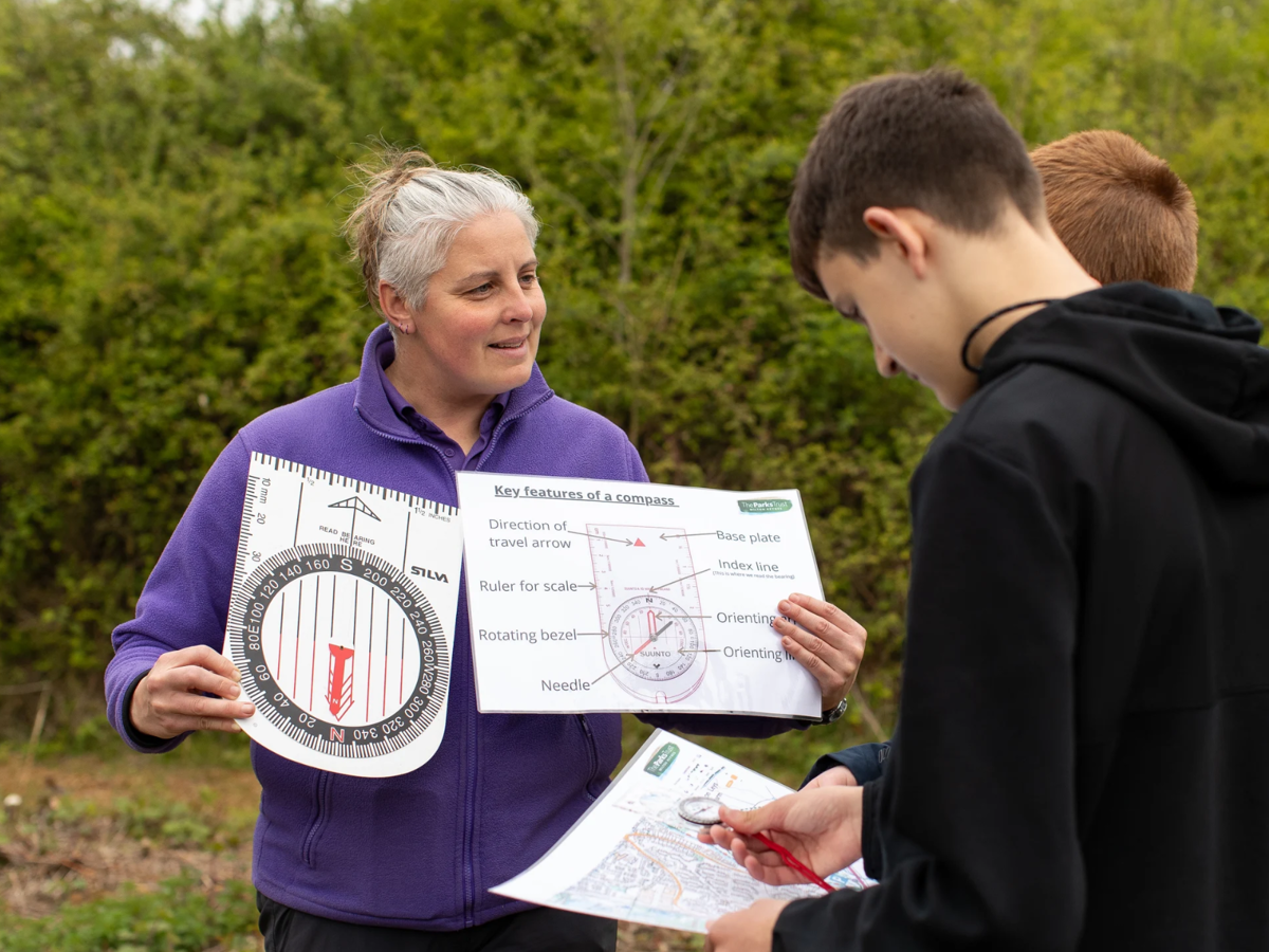 Students looking at map whilst an adults holds a large compass