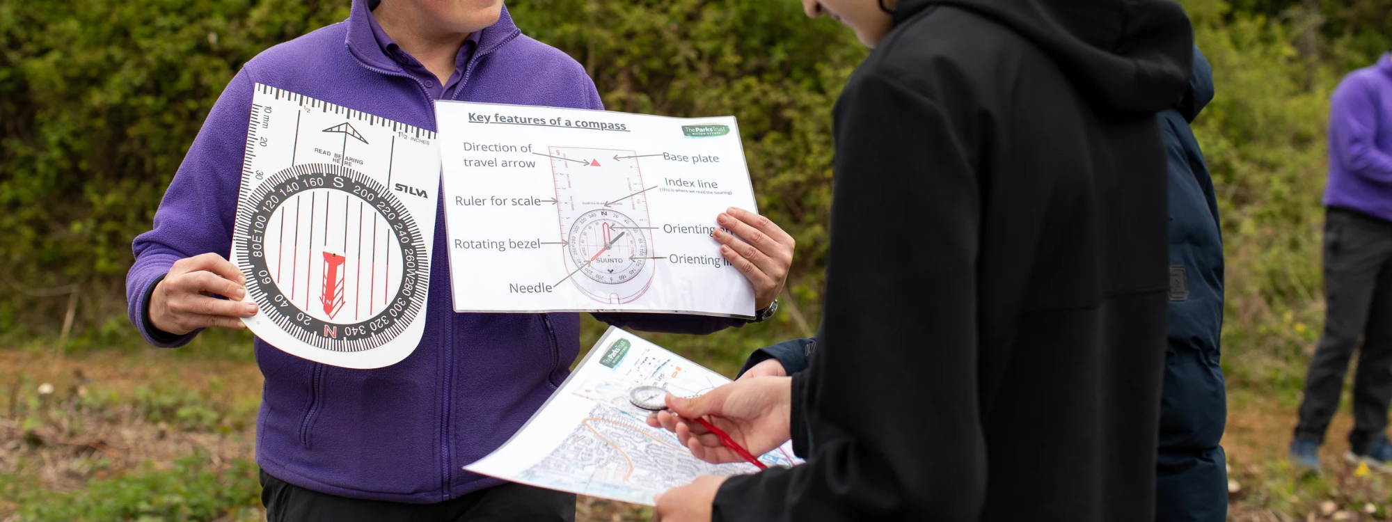 Students looking at map whilst an adults holds a large compass
